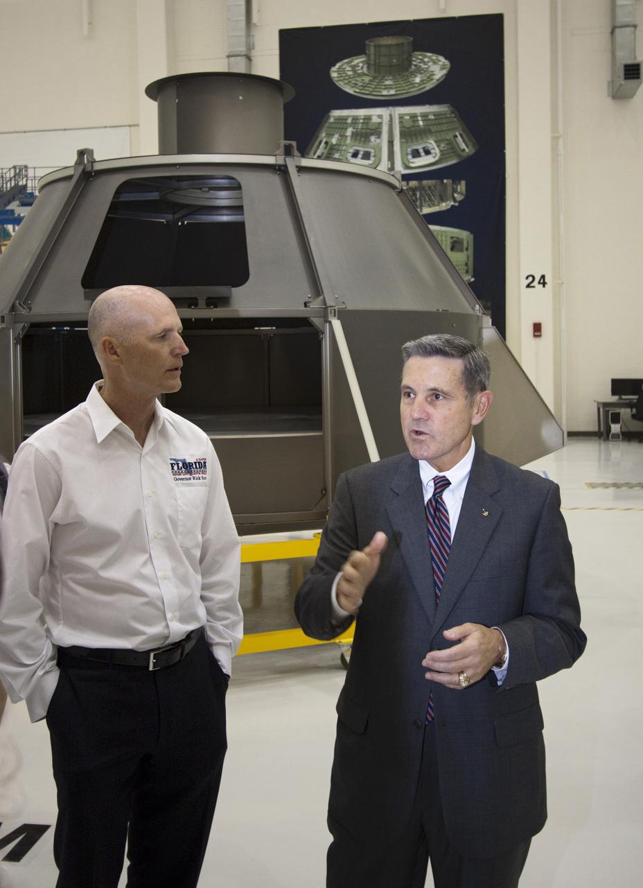 CAPE CANAVERAL, Fla. – In the Operations and Checkout Building at NASA's Kennedy Space Center in Florida, Robert Cabana, Kennedy Space Center director, (right), briefs Florida Gov. Rick Scott, (left), on the Orion Multi-Purpose Crew Vehicle. In the background is an Orion mock up used for testing.  The governor and other state officials were at Kennedy for a Florida cabinet meeting and a space industry roundtable at the Kennedy Space Center Visitor Complex’s Debus Conference Center. They also toured selected facilities around the center. Photo credit: NASA_Jim Grossmann
