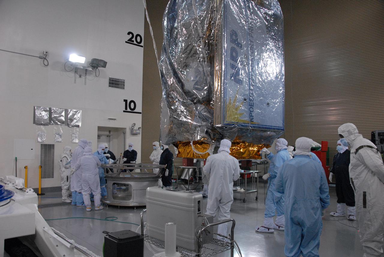 In a clean room inside the Astrotech Payload Processing Facility at Vandenberg Air Force Base in California, Ball Aerospace technicians prepare to attach NASA’s National Polar-orbiting Operational Environmental Satellite System Preparatory Project (NPP) spacecraft to a payload adapter. NPP represents a critical first step in building the next-generation of Earth-observing satellites. NPP will carry the first of the new sensors developed for this satellite fleet, now known as the Joint Polar Satellite System (JPSS), to be launched in 2016. NPP is the bridge between NASA's Earth Observing System (EOS) satellites and the forthcoming series of JPSS satellites. The mission will test key technologies and instruments for the JPSS missions. NPP is targeted to launch Oct. 28 from Space Launch Complex-2 aboard a United Launch Alliance Delta II rocket. For more information, visit http:__www.nasa.gov_NPP. Photo credit: NASA_Roy Allison, VAFB