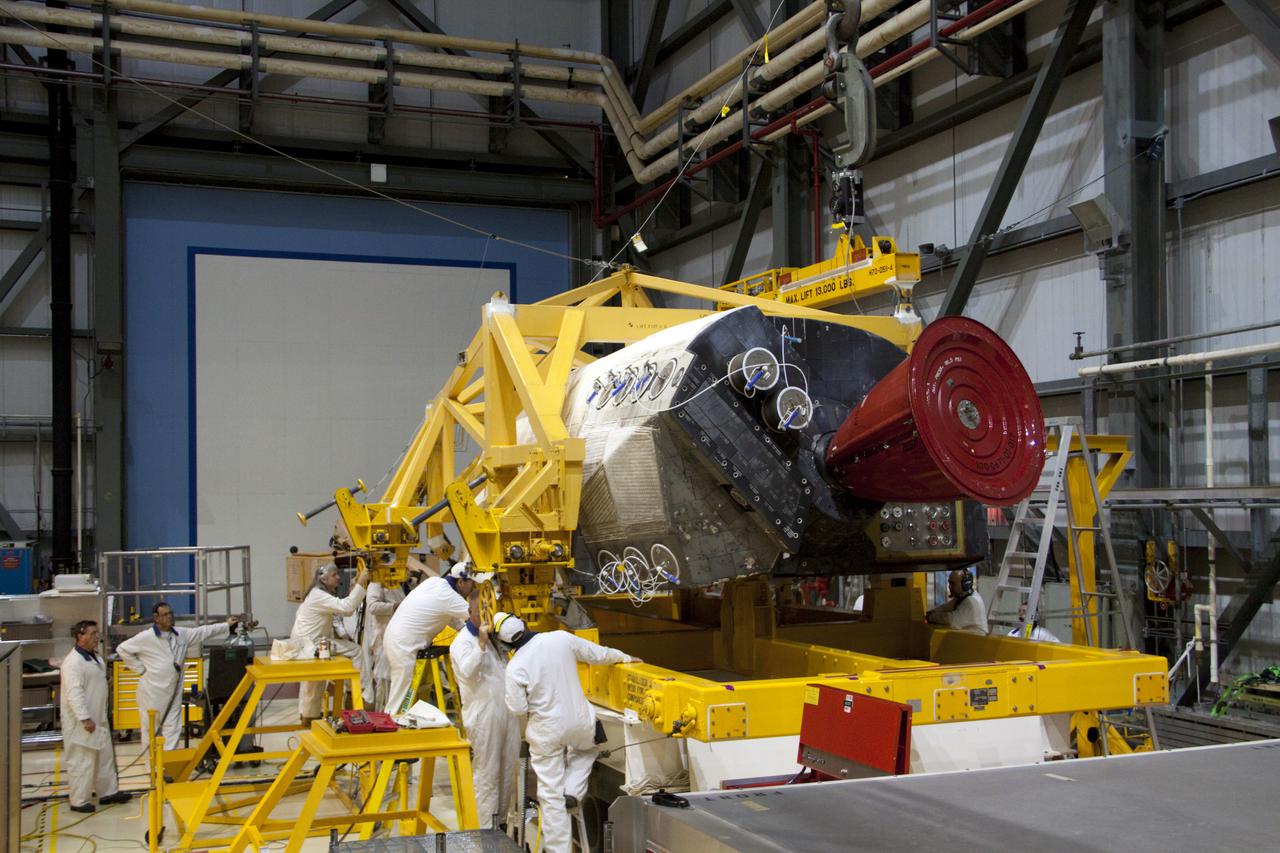 CAPE CANAVERAL, Fla. -- Inside Orbiter Processing Facility-2 at NASA’s Kennedy Space Center in Florida, technicians assist as a large crane lowers space shuttle Atlantis’ left orbital maneuvering system (OMS) pod onto a carrier.    The work is part of the Space Shuttle Program’s transition and retirement processing of shuttle Atlantis. The OMS pods will be sent to White Sands Space Harbor in New Mexico where they will undergo a complete deservicing and cleaning and then be returned to Kennedy for reinstallation on Atlantis.  Atlantis is being prepared for display at the Kennedy Space Center Visitor Complex in Florida.  Photo credit: NASA_Jim Grossmann