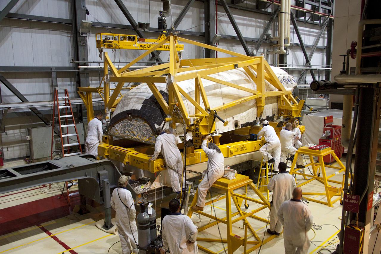 CAPE CANAVERAL, Fla. -- Inside Orbiter Processing Facility-2 at NASA’s Kennedy Space Center in Florida, technicians assist as a large crane lowers space shuttle Atlantis’ left orbital maneuvering system (OMS) pod onto a carrier.     The work is part of the Space Shuttle Program’s transition and retirement processing of shuttle Atlantis. The OMS pods will be sent to White Sands Space Harbor in New Mexico where they will undergo a complete deservicing and cleaning and then be returned to Kennedy for reinstallation on Atlantis.  Atlantis is being prepared for display at the Kennedy Space Center Visitor Complex in Florida.  Photo credit: NASA_Jim Grossmann