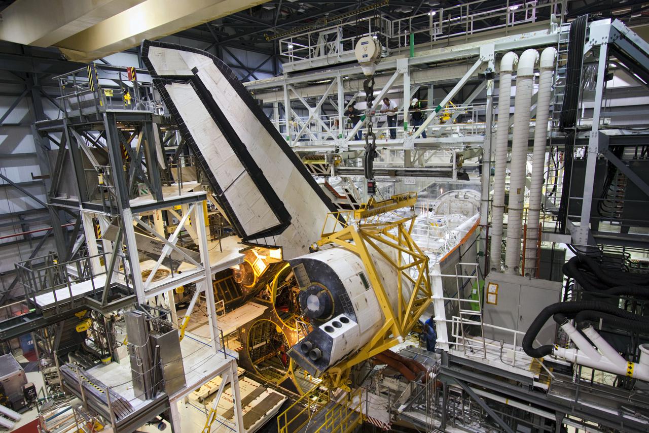 CAPE CANAVERAL, Fla. – Inside Orbiter Processing Facility-1 at NASA’s Kennedy Space Center in Florida, technicians monitor the progress as a crane moves the right orbital maneuvering system (OMS) pod closer for installation on space shuttle Discovery.  The OMS pods were returned from White Sands Space Harbor in New Mexico where they underwent a complete deservicing and cleaning. The work is part of the Space Shuttle Program’s transition and retirement processing of shuttle Discovery. Discovery is being prepared for display at Smithsonian’s National Air and Space Museum, Steven F. Udvar-Hazy Center in Chantilly, Va. For more information, visit http:__www.nasa.gov_shuttle.  Photo credit: NASA_Jim Grossmann