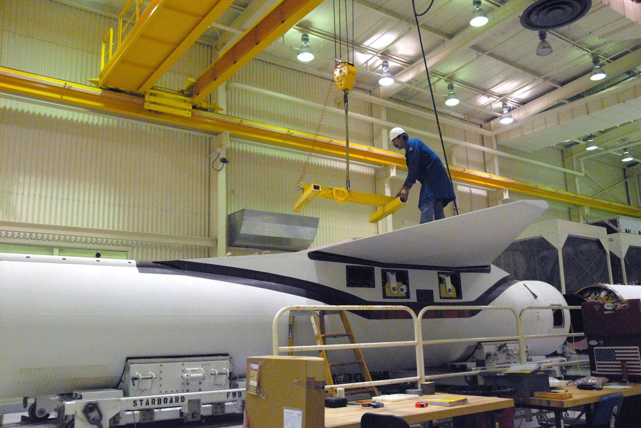 VANDENBERG AIR FORCE BASE, Calif. -- In a processing facility at Vandenberg Air Force Base in California, a technician helps guide a crane away after final wing installation on the Pegasus XL launch vehicle. The Orbital Sciences Corp. Pegasus rocket will launch the Nuclear Spectroscopic Telescope Array (NuSTAR) into space.    After the rocket and spacecraft are processed at Vandenberg, they will be flown on the Orbital Sciences’ L-1011 carrier aircraft to the Ronald Reagan Ballistic Missile Defense Test Site at the Pacific Ocean’s Kwajalein Atoll for launch. The high-energy x-ray telescope will conduct a census for black holes, map radioactive material in young supernovae remnants, and study the origins of cosmic rays and the extreme physics around collapsed stars. For more information, visit science.nasa.gov_missions_nustar_.  Photo credit: NASA_Randy Beaudoin, VAFB