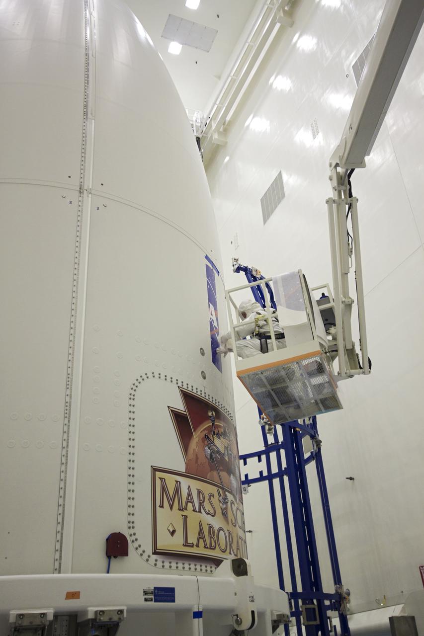 CAPE CANAVERAL, Fla. -- In the Payload Hazardous Servicing Facility at NASA's Kennedy Space Center in Florida, technicians begin applying the NASA logo above the Mars Science Laboratory (MSL) mission logo to the exterior of an Atlas V rocket's payload fairing. Tucked inside the fairing is the MSL spacecraft, including a compact car-sized rover, Curiosity, which has 10 science instruments designed to search for evidence on whether Mars has had environments favorable to microbial life, including the chemical ingredients for life. The unique rover will use a laser to look inside rocks and release its gasses so that the rover’s spectrometer can analyze and send the data back to Earth. Launch of MSL aboard a United Launch Alliance Atlas V rocket is planned for Nov. 25 from Space Launch Complex-41 on Cape Canaveral Air Force Station. For more information, visit http:__www.nasa.gov_msl. Photo credit: NASA_Jim Grossmann