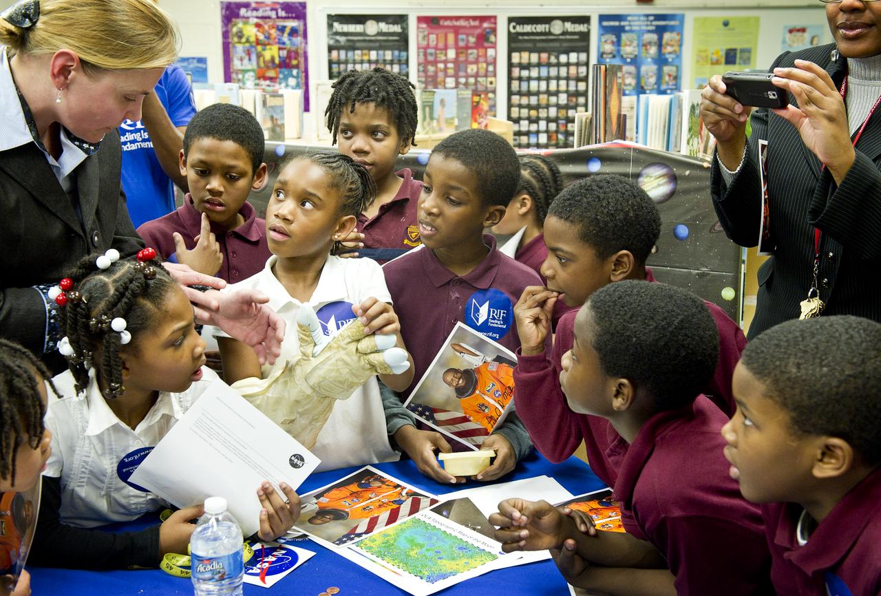 Betsy Pugel, far left, a physicist from NASA’s Goddard Space Flight Center in Greenbelt, Md., talks with students about the space suit glove they are trying on, Tuesday, Feb. 8, 2011 at Ferebee-Hope Elementary School in Washington, DC. Ferebee-Hope Elementary School, in collaboration with Reading is Fundamental (RIF), hosted this event in honor of Black History Month, and to highlight the importance of reading. Photo Credit: (NASA/Carla Cioffi) 