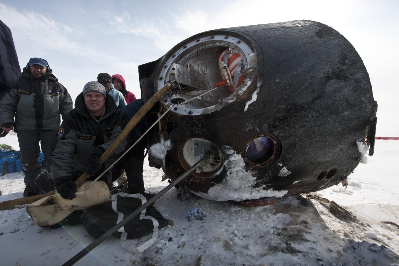 Russian support personnel work to help get crew members out of the Soyuz TMA-01M spacecraft shortly after the capsule landed with Expedition 26 Commander Scott Kelly and Flight Engineers Oleg Skripochka and Alexander Kaleri near the town of Arkalyk, Kazakhstan on Wednesday, March 16, 2011. NASA Astronaut Kelly, Russian Cosmonauts Skripochka and Kaleri are returning from almost six months onboard the International Space Station where they served as members of the Expedition 25 and 26 crews. Photo Credit: (NASA/Bill Ingalls)