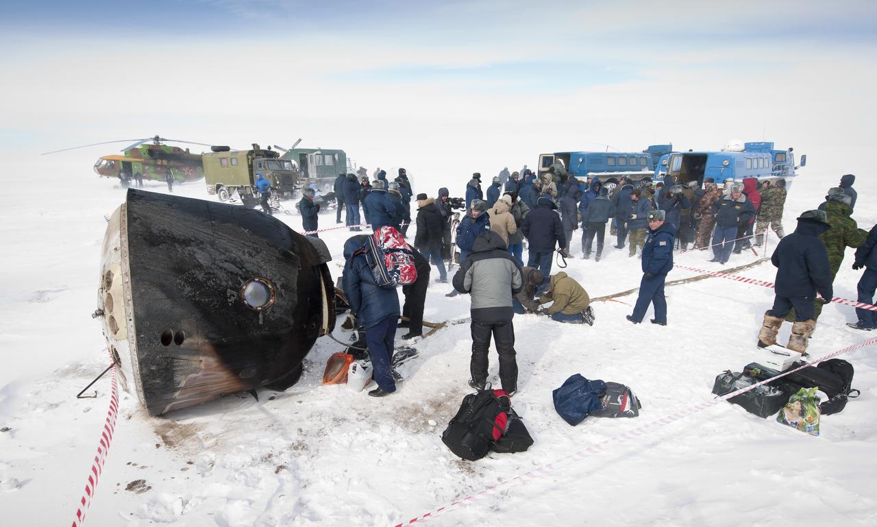 Russian support personnel work to help get crew members out of the Soyuz TMA-01M spacecraft shortly after the capsule landed with Expedition 26 Commander Scott Kelly and Flight Engineers Oleg Skripochka and Alexander Kaleri near the town of Arkalyk, Kazakhstan on Wednesday, March 16, 2011. NASA Astronaut Kelly, Russian Cosmonauts Skripochka and Kaleri are returning from almost six months onboard the International Space Station where they served as members of the Expedition 25 and 26 crews. Photo Credit: (NASA/Bill Ingalls)
