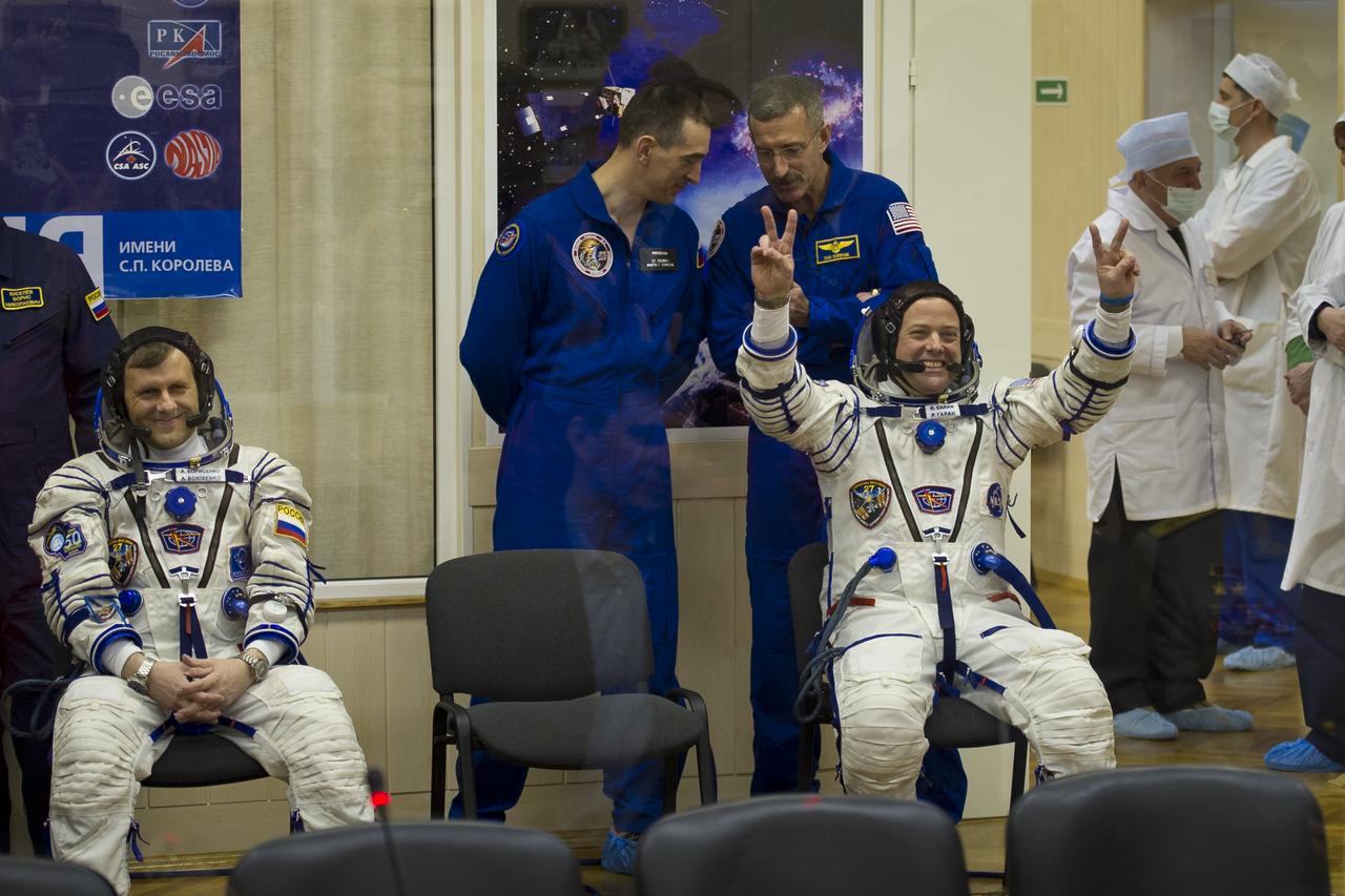 Expedition 27 Russian Flight Engineer Andrey Borisenko, sitting far left, smiles as NASA Flight Engineer Ron Garan flashes the peace sign to friends and family as they await to have their Russian Sokol suits prepared for launch on April 5, 2011 at the Baikonur Cosmodrome in Kazakhstan. Photo Credit: (NASA/Carla Cioffi)