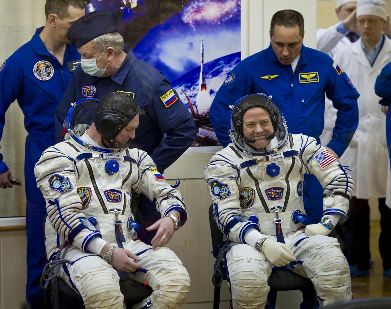 Expedition 27 NASA Flight Engineer Ron Garan, sitting right, smiles to friends and family while Soyuz Commander Alexander Samokutyaev checks his Russian Sokol Suit the morning of their launch on Tuesday, April 5, 2011 at the Baikonur Cosmodrome in Kazakhstan.  Photo Credit: (NASA/Carla Cioffi)