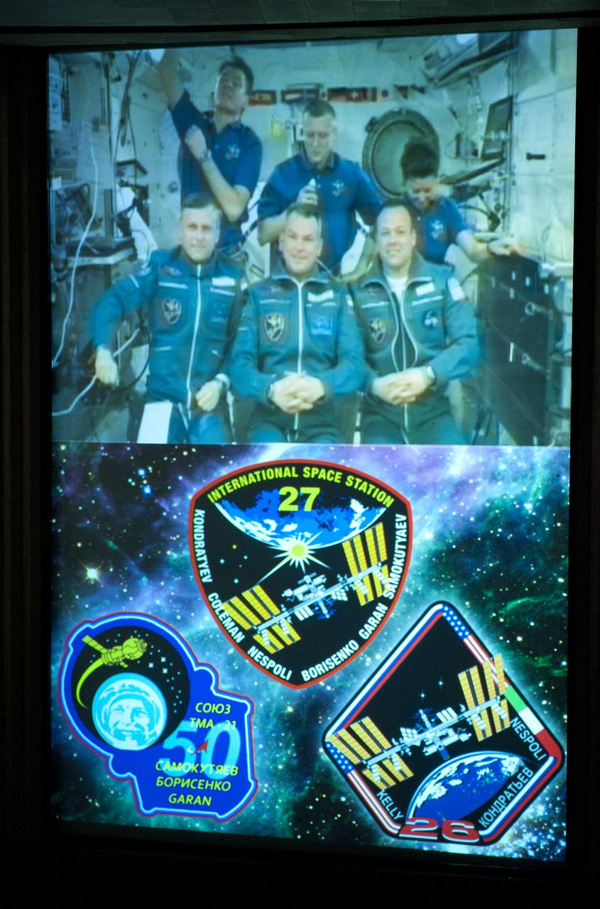 The crews of Expedition 26 and Expedition 27 are seen on a large screen TV at the Russian Mission Control Center in Korolev, Russia shortly after Expedition 27's arrival to the International Space Station on Thursday, April 7, 2011.  From top left clockwise: Italian Flight Engineer Paolo Nespoli, Expedition 27 Commander Dimitry Kondratiev, NASA Flight Engineer Cady Coleman, NASA Flight Engineer Ron Garan, Soyuz Commander Alexander Samokutyaev and Flight Engineer Andrey Borisenko.  Photo Credit: (NASA/Carla Cioffi)