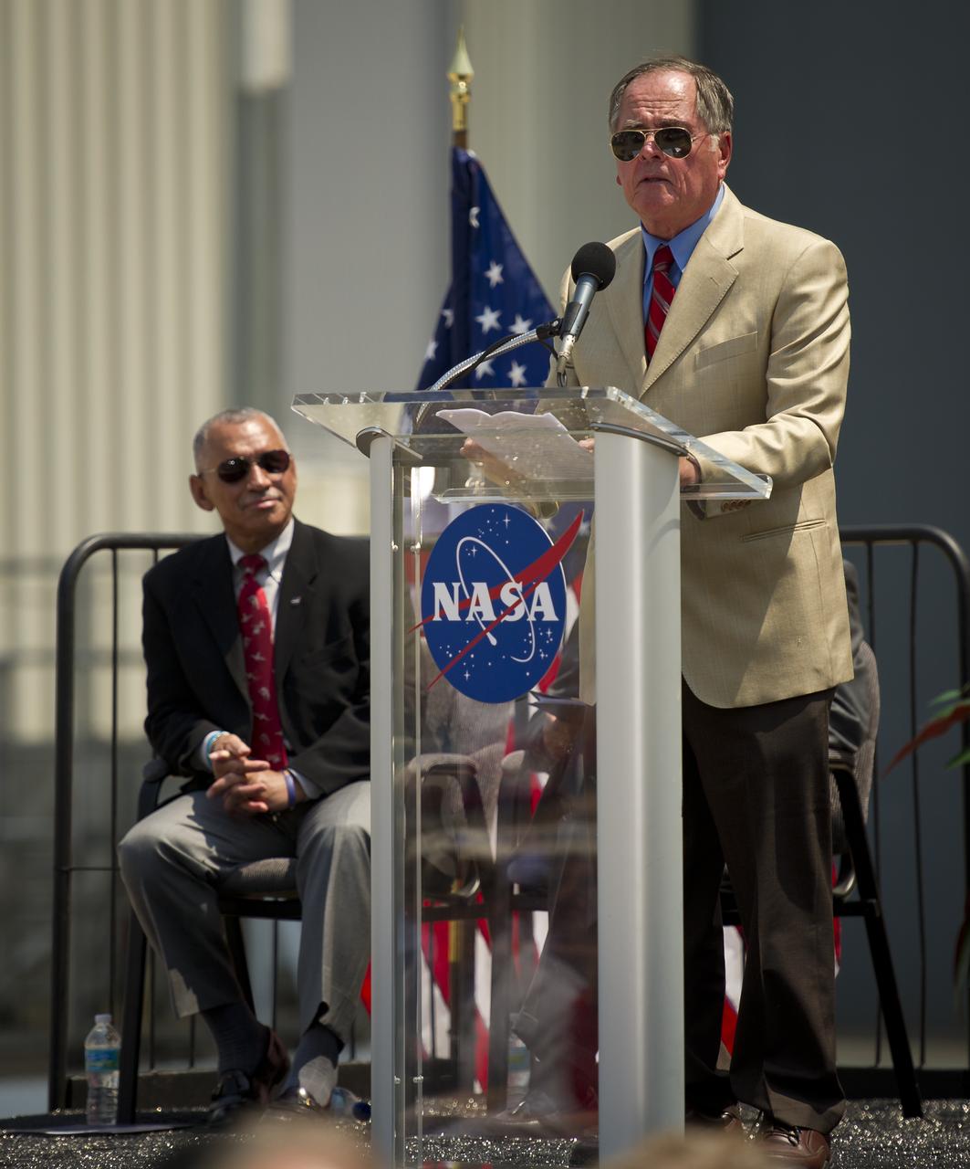 Pilot of the first space shuttle mission, STS-1, Bob Crippen speaks at an event where NASA Administrator Charles Bolden announced where four space shuttle orbiters will be permanently displayed at the conclusion of the Space Shuttle Program, Tuesday, April 12, 2011, at Kennedy Space Center in Cape Canaveral, Fla. The four orbiters, Enterprise, which currently is on display at the Smithsonian's Steven F. Udvar-Hazy Center near Washington Dulles International Airport, will move to the Intrepid Sea, Air & Space Museum in New York, Discovery will move to Udvar-Hazy, Endeavour will be displayed at the California Science Center in Los Angeles and Atlantis, in background, will be displayed at the Kennedy Space Center Visitor’s Complex.  Photo Credit: (NASA/Bill Ingalls)