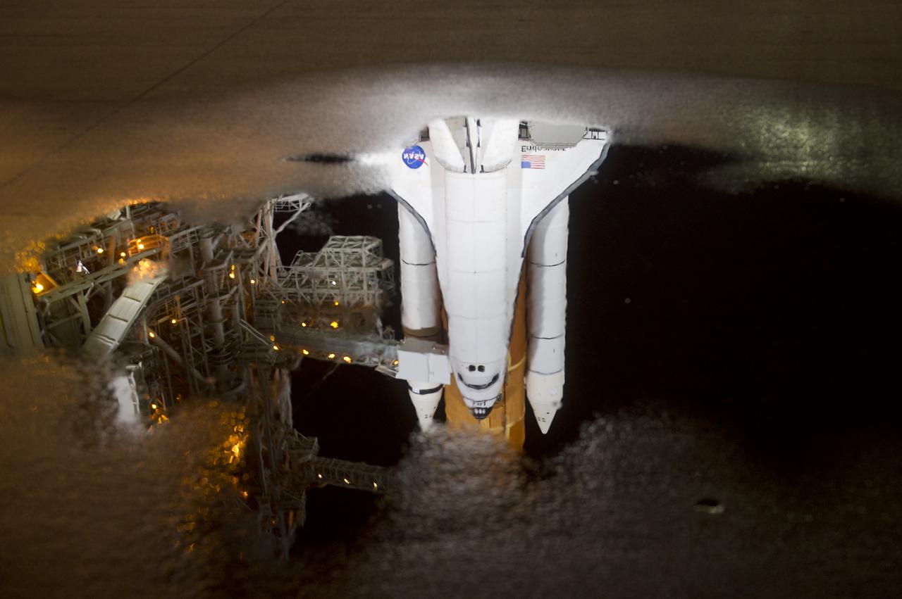 The space shuttle Endeavour is seen reflected in a puddle of water on launch pad 39a after the rollback of the Rotating Service Structure (RSS), Thursday, April 28, 2011, at Kennedy Space Center in Cape Canaveral, Fla. During the 14-day mission, Endeavour and the STS-134 crew will deliver the Alpha Magnetic Spectrometer (AMS) and spare parts including two S-band communications antennas, a high-pressure gas tank and additional spare parts for Dextre. Launch is targeted for Friday, April 29 at 3:47 p.m. EDT.  Photo credit: (NASA/Bill Ingalls)