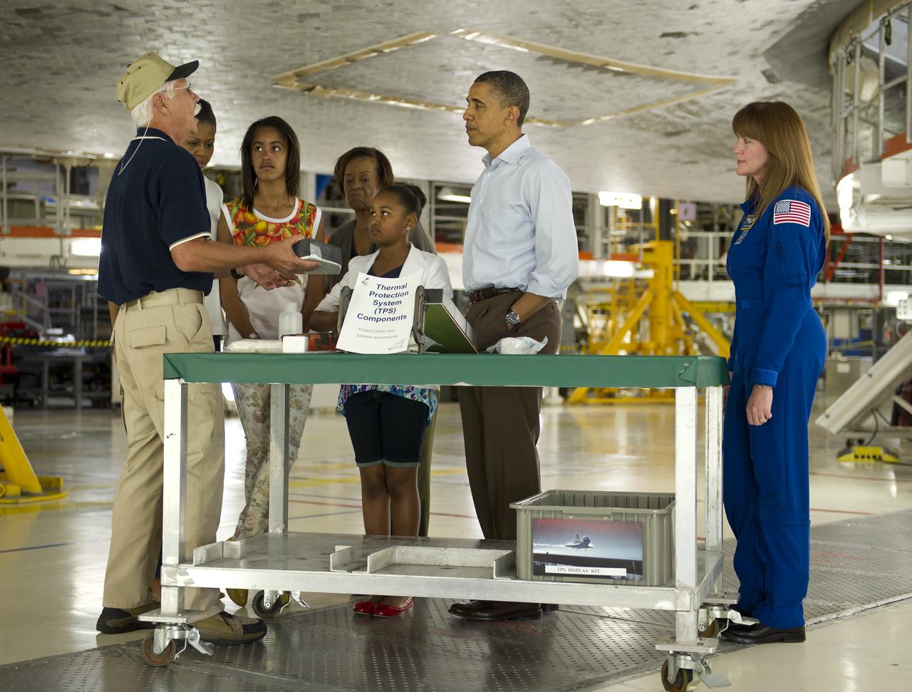 Terry White, United Space Alliance project lead for thermal protection systems, left, shows President Barack Obama and his family, from left, First Lady Michelle Obama, Malia, Marian Robinson and Sasha, how tiles work on the space shuttle during their visit to the Orbital Processing Facility at the NASA Kennedy Space Center in Cape Canaveral, Fla., Friday, April 29, 2011. Looking on is Director of Flight Crew Operations for the Johnson Space Center and Astronaut, Janet Kavandi. Photo Credit: (NASA/Bill Ingalls)