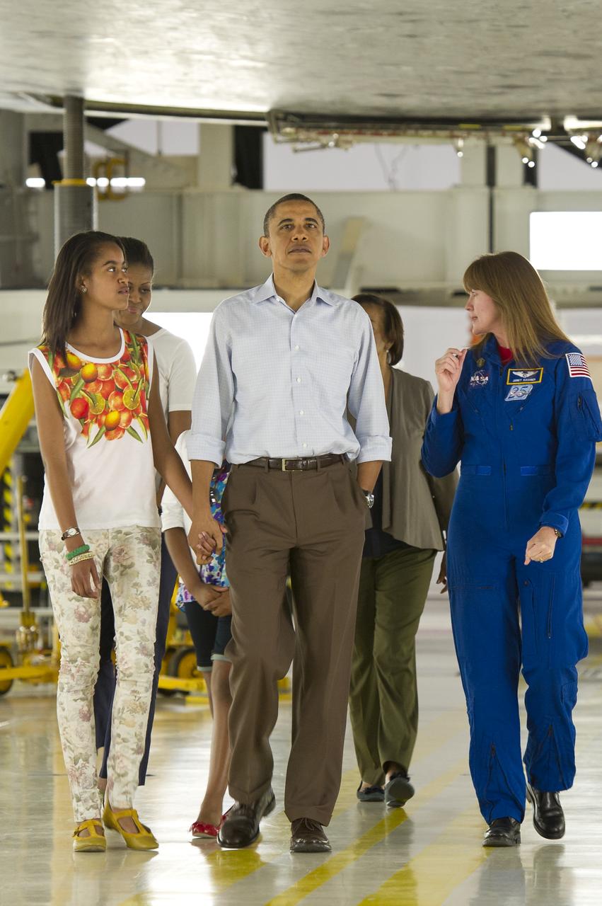 President Barack Obama holds hands with his daughter Malia as they walk under the space shuttle Atlantis during a tour the first family received of the the NASA Orbital Processing Facility given by Director of Flight Crew Operations for the Johnson Space Center and Astronaut, Janet Kavandi, right, at the NASA Kennedy Space Center in Cape Canaveral, Fla., Friday, April 29, 2011. Photo Credit: (NASA/Bill Ingalls)