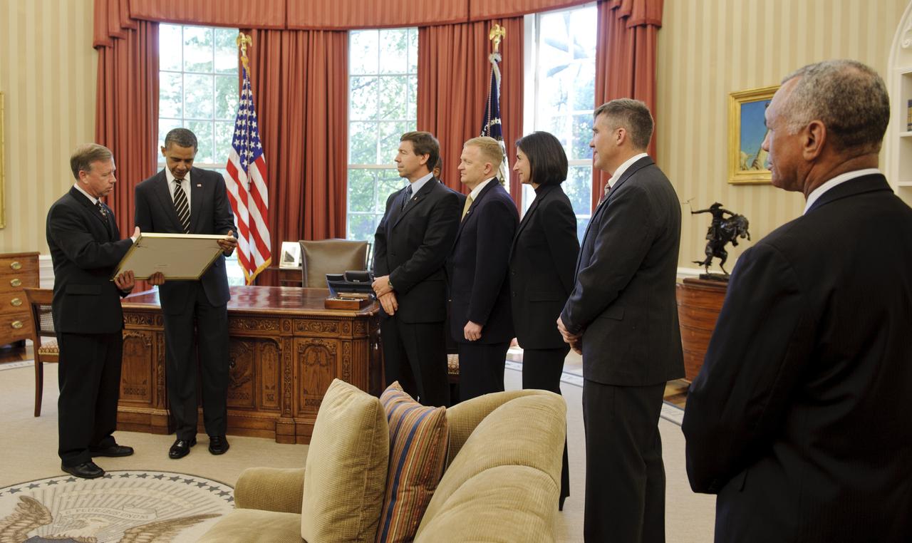 STS-133 Commander Steven Lindsey, far left, presents a montage to President Barack Obama as crew members Michael Barratt, Pilot Eric Boe, Nicole Stott, and Stephen Bowen along with NASA Administrator Charles Bolden, far right, look on during a visit to the Oval Office in the White House, Monday, May 9, 2011, in Washington. Also in attendance but not seen, was Mission Specialist Alvin Drew.Photo Credit: (NASA/Paul E. Alers)