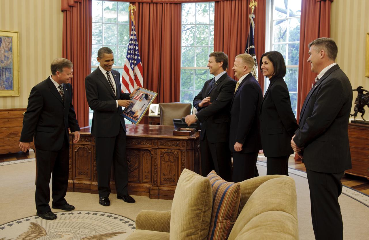 STS-133 Commander Steven Lindsey, far left, presents a montage to President Barack Obama as crew members Michael Barratt, Pilot Eric Boe, Nicole Stott, and Stephen Bowen look on during a visit to the Oval Office in the White House, Monday, May 9, 2011, in Washington. Also in attendance but not seen, was Mission Specialist Alvin Drew. Photo Credit: (NASA/Paul E. Alers)