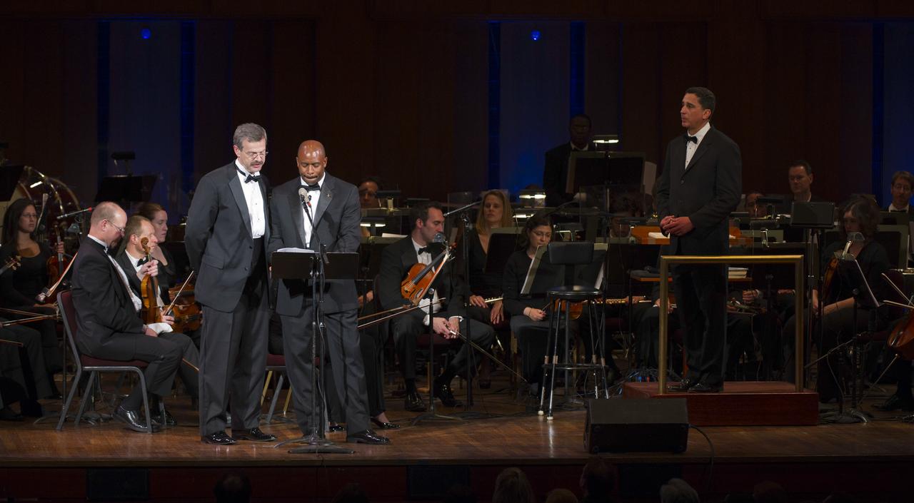 Astronauts Scott Altman, left, and Leland Melvin speak of their fallen comrades as Emil de Cou, right, looks on during a program commemorating Human Spaceflight and the Kennedy Legacy, Wednesday, May 25, 2011, in the concert hall at the John F. Kennedy Center for the Performing Arts in Washington. The event marked the 50th Anniversary of President John F. Kennedy's Special Message to the Congress on Urgent National Needs in which he stated "landing a man on the moon and returning him safely to earth". Photo Credit: (NASA/Paul E. Alers)