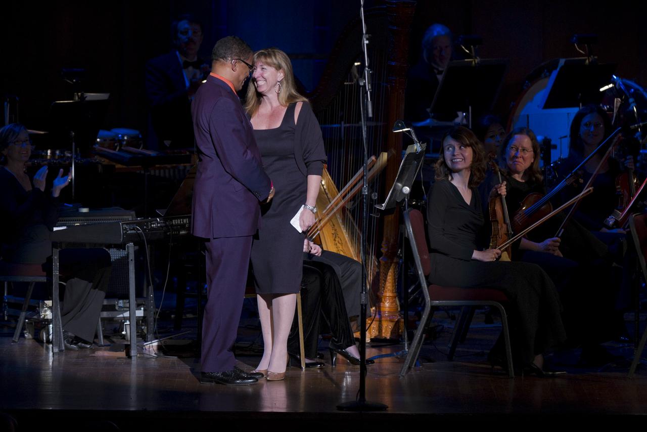Deputy Administrator Lori Garver, right, smiles after introducing musical guest Herbie Hancock, left, as members of the Space Philharmonic look on during a program commemorating Human Spaceflight and the Kennedy Legacy, Wednesday, May 25, 2011, in the concert hall at the John F. Kennedy Center for the Performing Arts in Washington. The event marked the 50th Anniversary of President John F. Kennedy's Special Message to the Congress on Urgent National Needs in which he stated "landing a man on the moon and returning him safely to earth". Photo Credit: (NASA/Paul E. Alers)