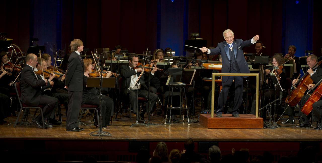 Former Apolo 11 astronaut Buzz Aldrin guest conducts the Space Philharmonic as Ted Kennedy III, left, looks on during a program commemorating Human Spaceflight and the Kennedy Legacy, Wednesday, May 25, 2011, in the concert hall at the John F. Kennedy Center for the Performing Arts in Washington. The event marked the 50th Anniversary of President John F. Kennedy's Special Message to the Congress on Urgent National Needs in which he stated "landing a man on the moon and returning him safely to earth". Photo Credit: (NASA/Paul E. Alers)