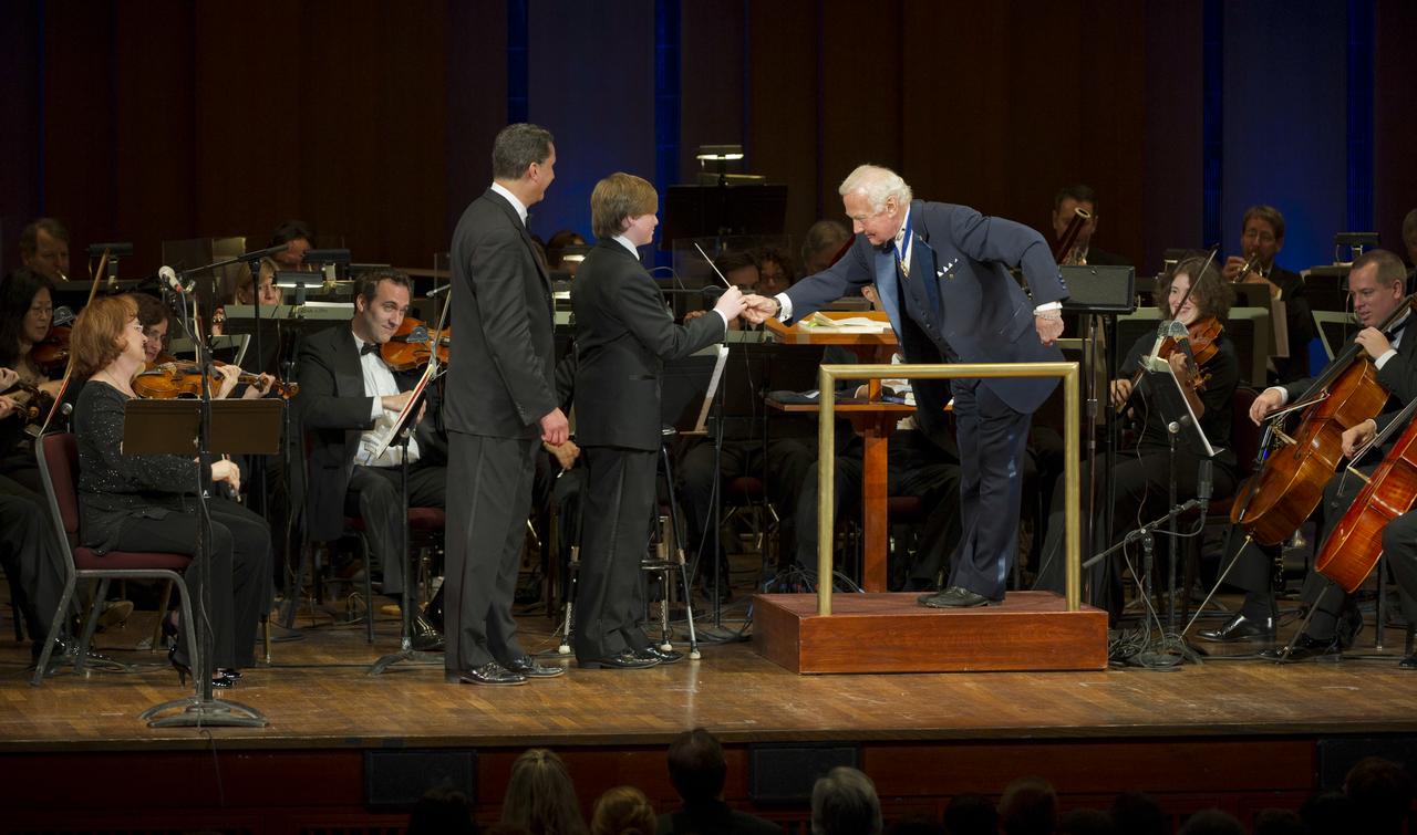Former Apolo 11 astronaut Buzz Aldrin, right, passes the baton to second guest conductor Ted Kennedy III as conductor Emil de Cou looks on while the Space Philharmonic plays on during a program commemorating Human Spaceflight and the Kennedy Legacy, Wednesday, May 25, 2011, in the concert hall at the John F. Kennedy Center for the Performing Arts in Washington. The event marked the 50th Anniversary of President John F. Kennedy's Special Message to the Congress on Urgent National Needs in which he stated "landing a man on the moon and returning him safely to earth". Photo Credit: (NASA/Paul E. Alers)