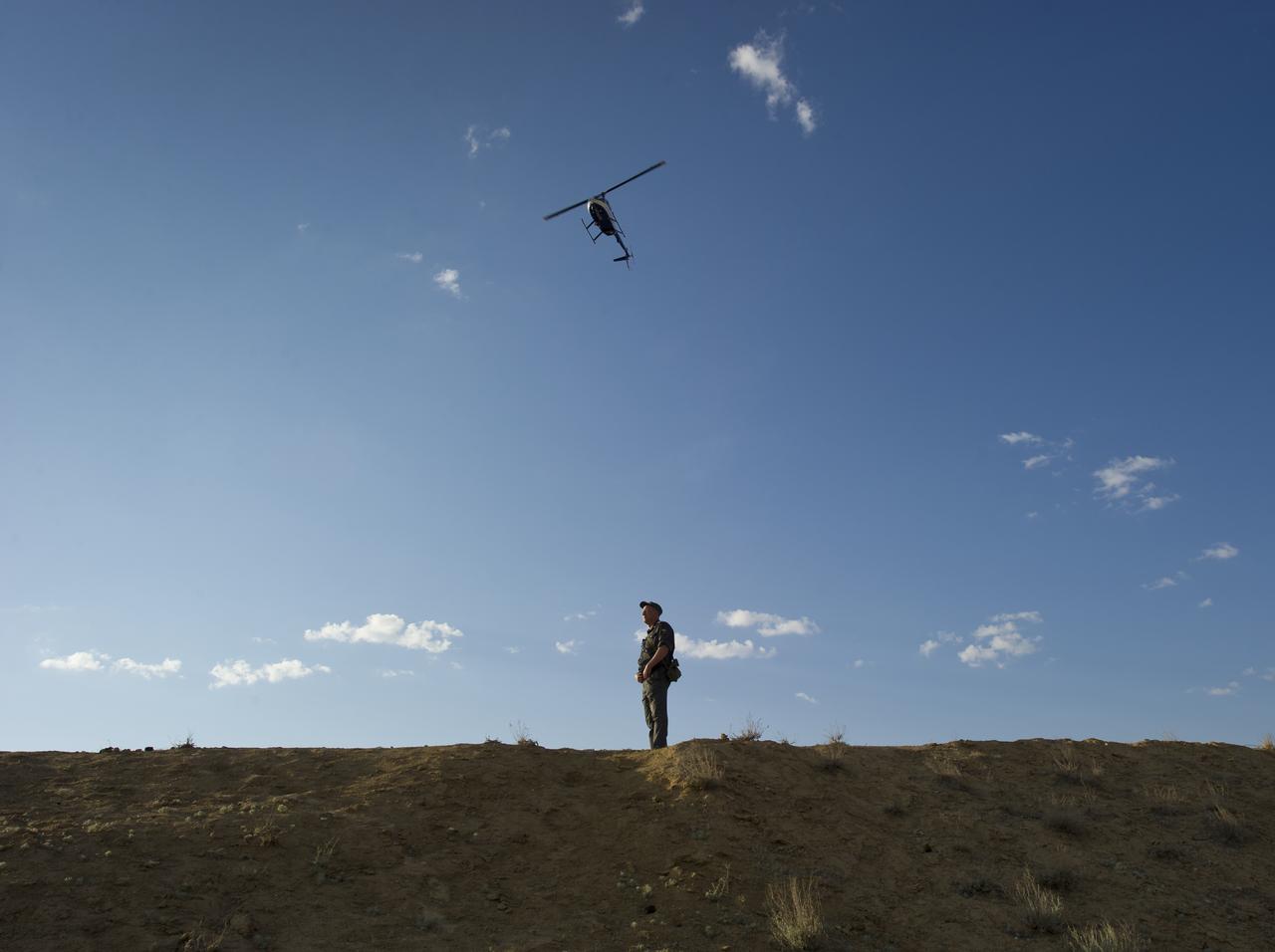 A Russian security guard stands watch as a Russian military helicopter flies overhead during the rollout of the Soyuz TMA-02M rocket to the launch pad at the Baikonur Cosmodrome in Kazakhstan on Sunday, June 5, 2011.  Photo Credit:  (NASA/Carla Cioffi)