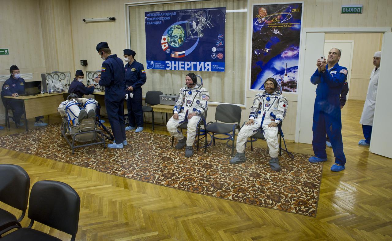NASA astronaut and Expedition 28 Flight Engineer Mike Fossum, third from right sitting, and JAXA (Japanese Aerospace Exploration Agency) Flight Engineer Satoshi Furukawa, second from right, sit while Expedition 28 Soyuz Commander Sergei Volkov has his Russian Sokol suit pressure checked on Tuesday, June 7, 2011 at the Baikonur Cosmodrome in Kazakhstan.  Volkov, Fossum and Furukawa are scheduled to launch in the Soyuz TMA-02M spacecraft to the International Space Station the following morning on June 8th.  Photo Credit:  (NASA/Carla Cioffi)