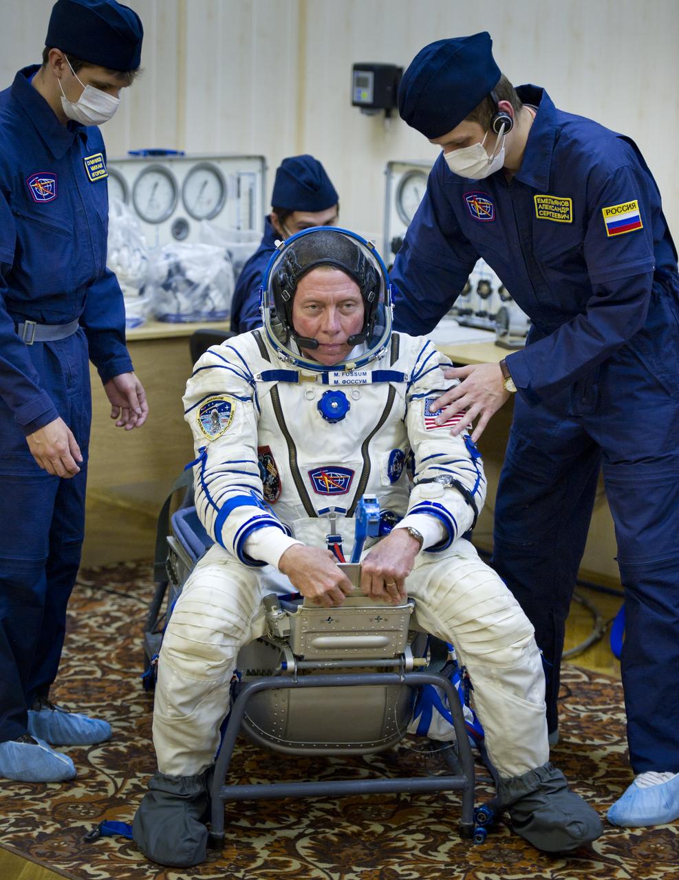 Expedition 28 and NASA astronaut Mike Fossum is helped by Russian suit technicians to a chair where his Russian Sokol suit will be pressure checked in preparation for his launch to the International Space Station, Tuesday, June 7, 2011 at the Baikonur Cosmodrome in Kazakhstan. The Soyuz spacecraft will launch the following morning on June 8 carrying Expedition 28 Soyuz Commander Sergei Volkov, JAXA (Japanese Aerospace Exploration Agency) Flight Engineer Satoshi Furukawa and Fossum. Photo Credit: (NASA/Carla Cioffi)