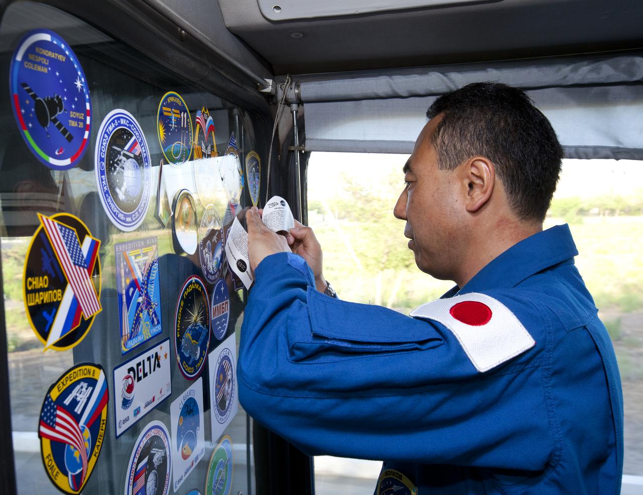 Expedition 28 JAXA (Japan Aerospace Exploration Agency) Flight Engineer Satoshi Furukawa places a mission sticker on the inside wall of the prime crew bus on the eve of his launch to the International Space Station, Tuesday, June 7, 2011 at the Baikonur Cosmodrome in Kazakhstan.  Photo Credit: (NASA/Roscosmos/Andrey Shelepin)