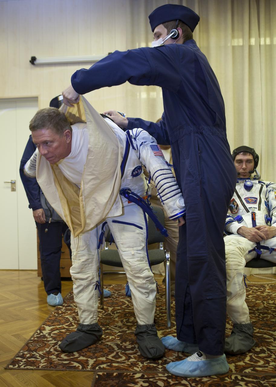 Expedition 28 NASA Flight Engineer Mike Fossum has his Russian Sokol suit prepared for launch by a technician at the Baikonur Cosmodrome in Baikonur, Kazakhstan, Tuesday, June 7, 2011.  Fossum and fellow Expedition 28 crew members Soyuz Commander Sergei Volkov and JAXA (Japanase Aerospace Exploration Agency) Flight Engineer Satoshi Furukawa launched in their Soyuz TMA-02M rocket from the Baikonur Cosmodrome in Kazakhstan the following morning on June 8th. Photo Credit: (NASA/Roscosmos/Andrey Shelepin)