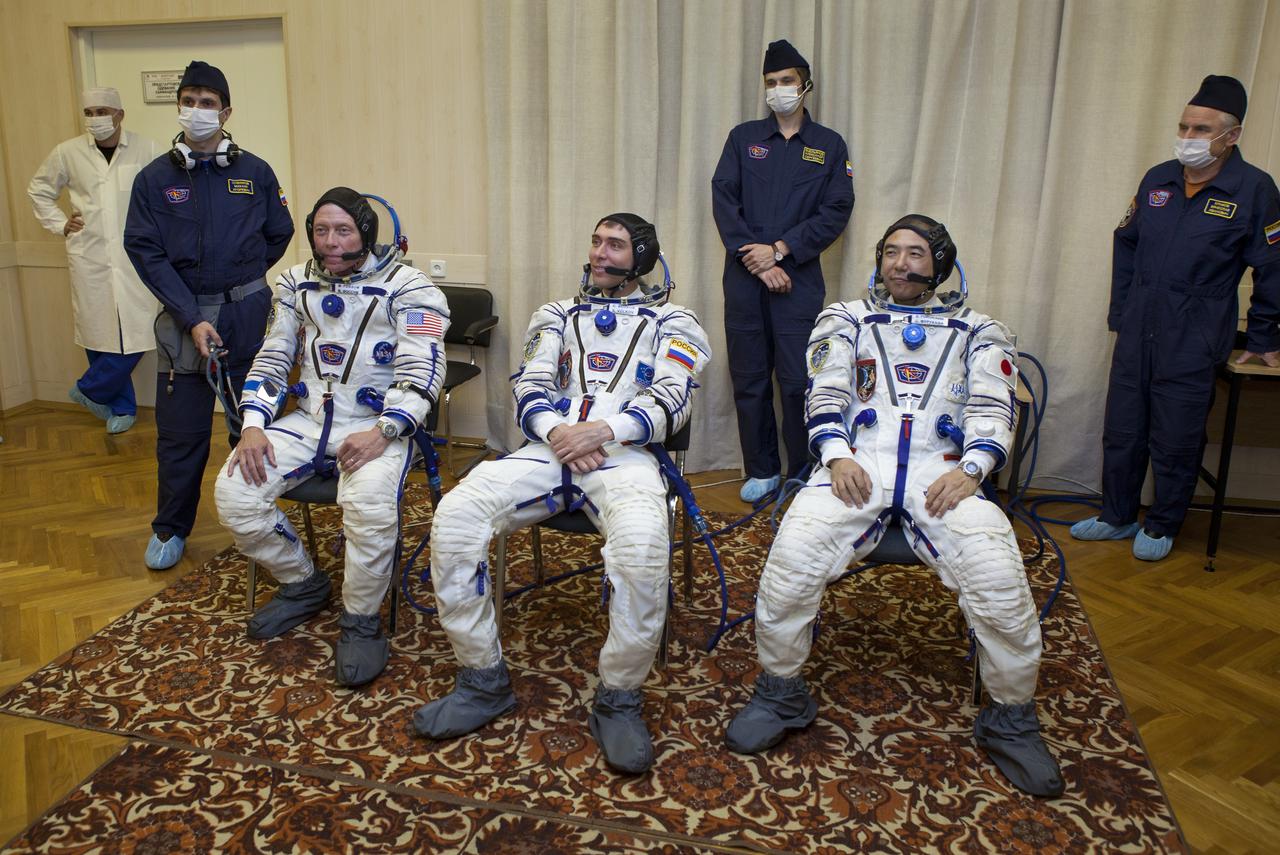 Expedition 28 NASA Flight Engineer Mike Fossum, left, Soyuz Commander Sergei Volkov of Russia, and JAXA (Japan Aerospace Exploration Agency) Flight Engineer Satoshi Furukawa, right, have their Russian Sokol suits prepared for launch by a technicians at the Baikonur Cosmodrome in Baikonur, Kazakhstan, Tueday, June 7, 2011.  Fossum, Volkov and Furukawa and launched in their Soyuz TMA-02M rocket from the Baikonur Cosmodrome in Kazakhstan the following morning on June 8th. Photo Credit: (NASA/Roscosmos/Andrey Shelepin)