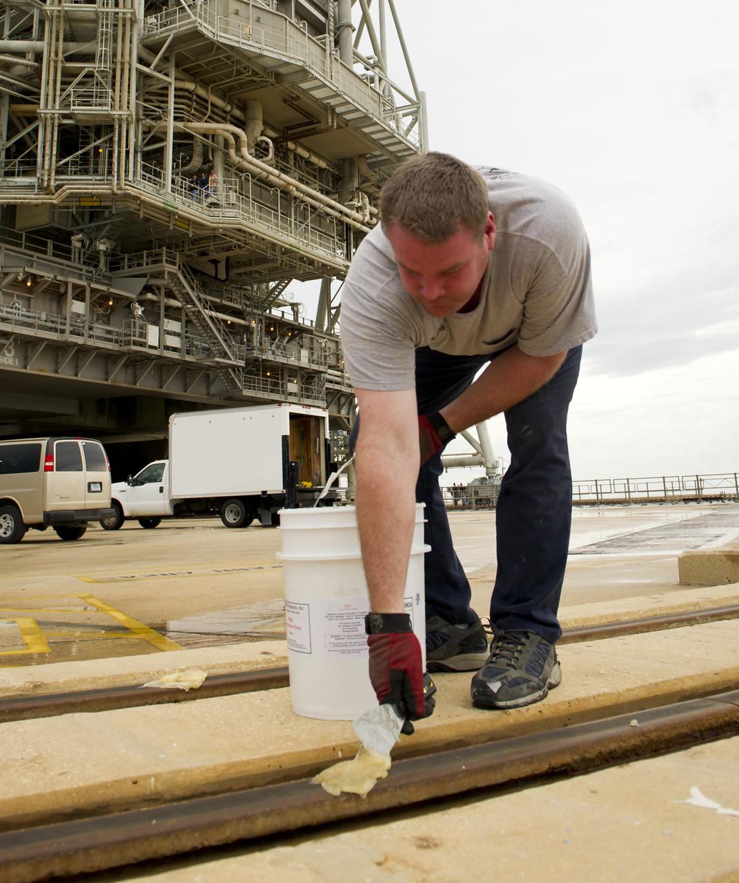 Launch pad worker Chris Cassidy lays down grease on the tracks of the rotating service structure (RSS) on launch pad 39a prior to the RSS being rolled back to reveal the space shuttle Atlantis on Thursday, July 7, 2011 at the NASA Kennedy Space Center in Cape Canaveral, Fla.  Space shuttle Atlantis is set to liftoff Friday, July 8, on the final flight of the shuttle program, STS-135, a 12-day mission to the International Space Station.  Photo Credit: (NASA/Bill Ingalls)