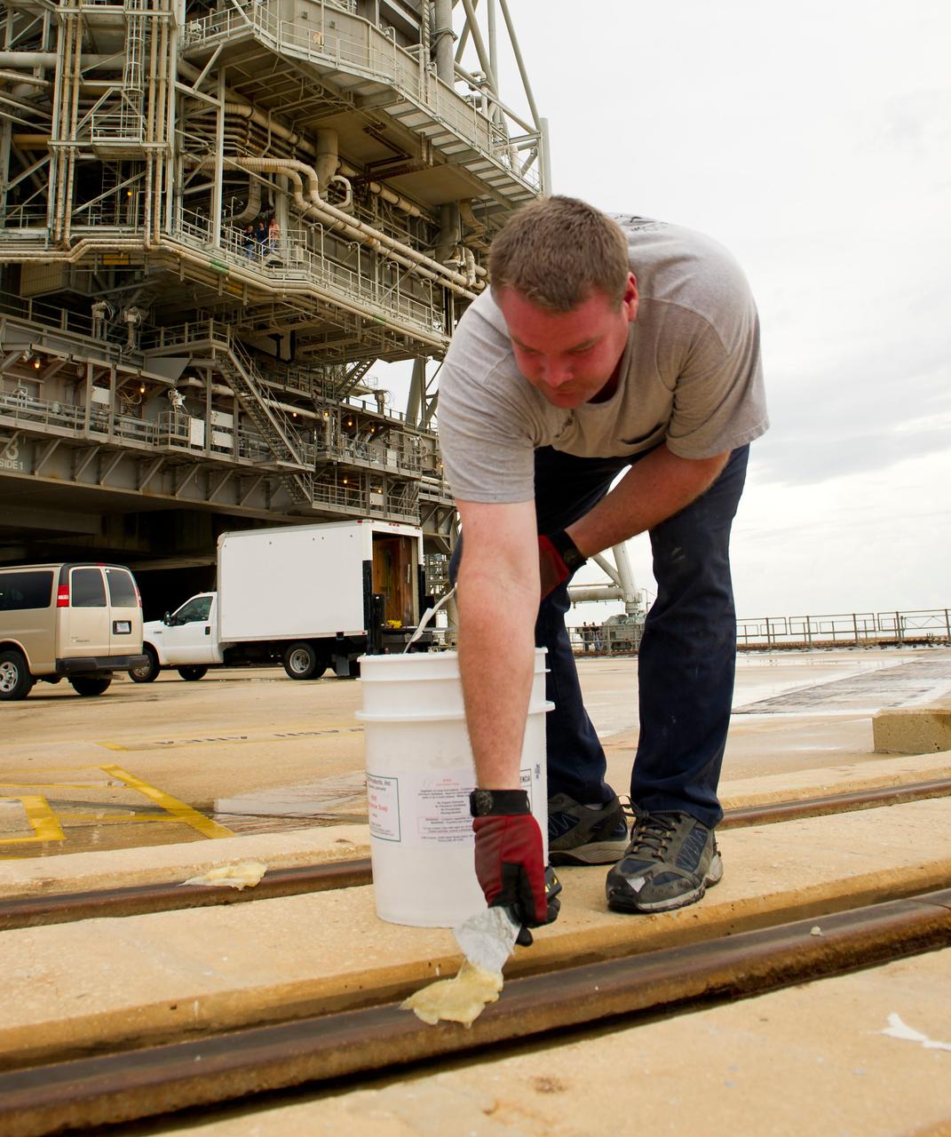 Launch pad worker Chris Cassidy lays down grease on the tracks of the rotating service structure (RSS) on launch pad 39a prior to the RSS being rolled back to reveal the space shuttle Atlantis on Thursday, July 7, 2011 at the NASA Kennedy Space Center in Cape Canaveral, Fla.  Space shuttle Atlantis is set to liftoff Friday, July 8, on the final flight of the shuttle program, STS-135, a 12-day mission to the International Space Station.  Photo Credit: (NASA/Bill Ingalls)