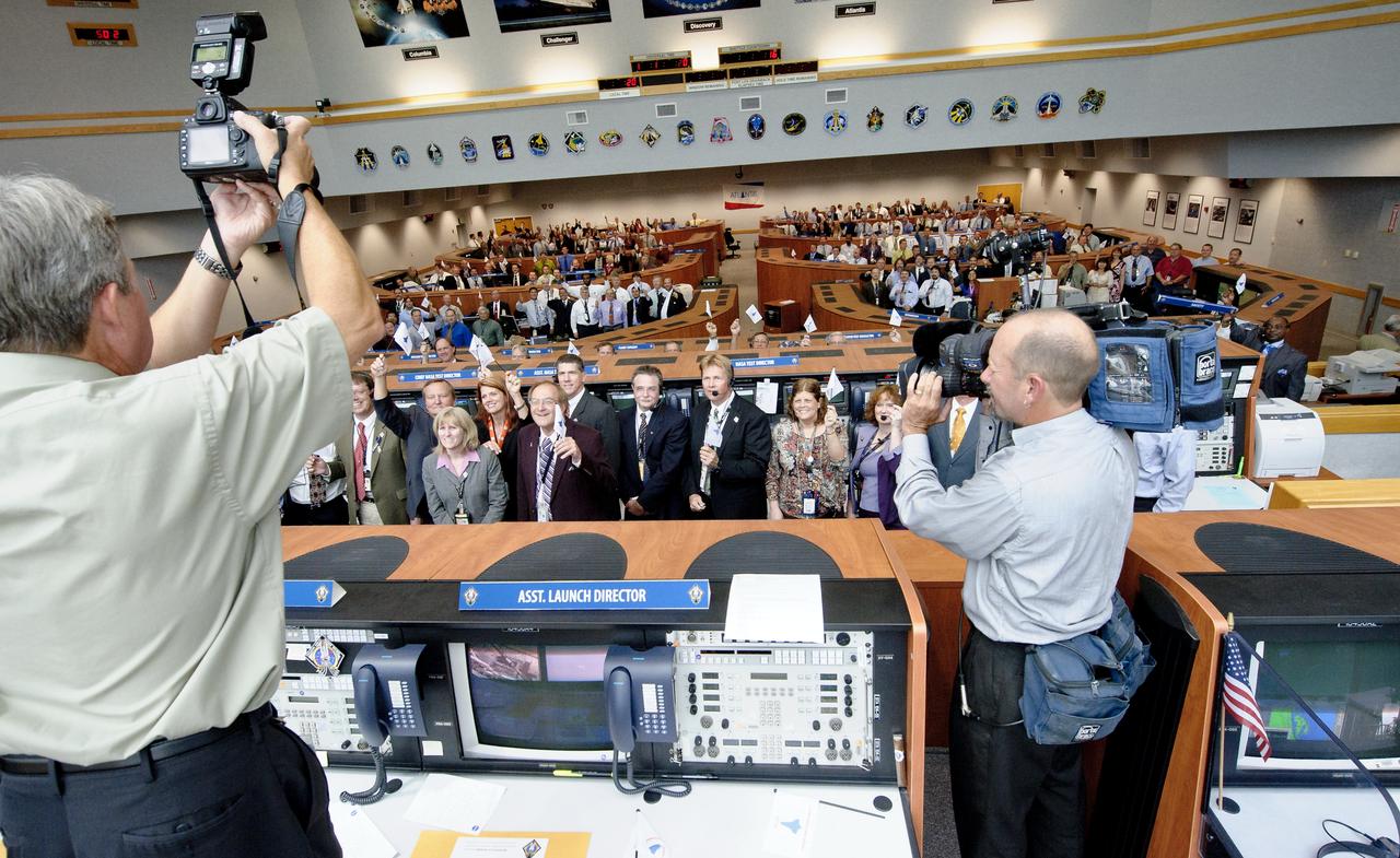 NASA Photographer Kim Shiflett, left, and Videographer Glenn Benson capture a group photo of the launch team in Firing Room Four of the NASA Kennedy Space Center Launch Control Center (LCC) shortly after the space shuttle Atlantis, STS-135, launched on Friday, July 8, 2011, in Cape Canaveral, Fla. The launch of Atlantis is the final flight of the shuttle program, a 12-day mission to the International Space Station.  Photo Credit: (NASA/Bill Ingalls)