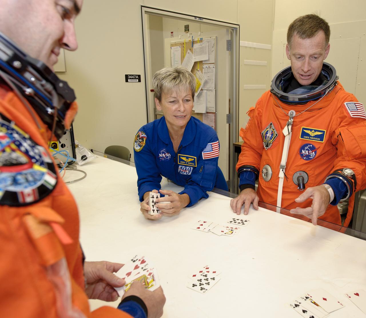 NASA Chief, Astronaut Office, Johnson Space Center Peggy Whitson, center, STS-135 Astronauts, Rex Walheim, left, and Commander Chris Ferguson are seen as the entire crew plays a traditional card game at the NASA Kennedy Space Center Operations and Checkout Building prior to them leaving for the launch pad, on Friday, July 8, 2011 in Cape Canaveral, Fla. The point of the game is that the commander must use up all his or her bad luck before launch, so the crew can only leave for the pad after the commander loses. The launch of Atlantis, STS-135, is the final flight of the shuttle program, a 12-day mission to the International Space Station. Photo Credit: (NASA/Jerry Ross)