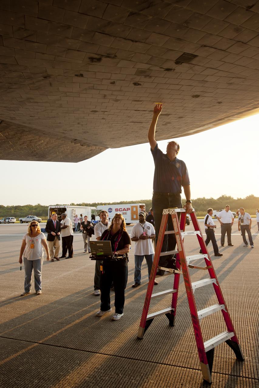 NASA and contractor personnel work under the space shuttle Atlantis at the Kennedy Space Center Shuttle Landing Facility (SLF) shortly after Atlantis (STS-135) landed early Thursday morning, July 21, 2011, in Cape Canaveral, Fla. Overall, Atlantis spent 307 days in space and traveled nearly 126 million miles during its 33 flights. Atlantis, the fourth orbiter built, launched on its first mission on Oct. 3, 1985. Photo Credit: (NASA/Bill Ingalls)