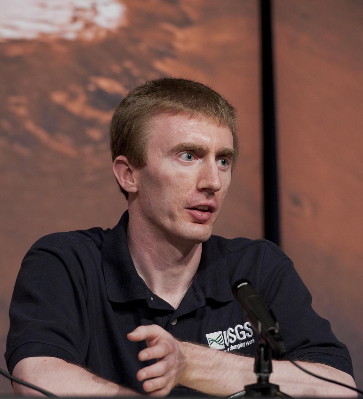 Colin Dundas, a research geologist with the U.S. Geological Survey, speaks during a briefing, Thursday, Aug. 4, 2011, at NASA Headquarters in Washington. Observations from NASA's Mars Reconnaissance Orbiter (MRO) have revealed possible flowing water during the warmest months on Mars. Dark, finger-like features appear and extend down some Martian slopes during late spring through summer, fade in winter, and return during the next spring. Repeated observations have tracked the seasonal changes in these recurring features on several steep slopes in the middle latitudes of Mars' southern hemisphere. Photo Credit: (NASA/Paul E. Alers)
