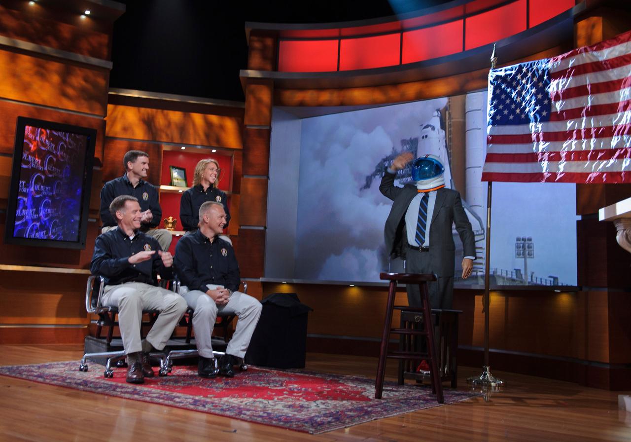201108160008hq (16 Aug. 2011) --- Stephen Colbert, host of The Colbert Report, salutes the crew of STS-135, seated from lower left, NASA astronauts Chris Ferguson, commander; Doug Hurley, pilot; Sandy Magnus and Rex Walheim, both mission specialists, during their appearance for a taping of his television show, Aug. 16, 2011, in New York. The astronauts from STS-135 are in New York for a three-day visit. Photo credit: NASA/Paul E. Alers