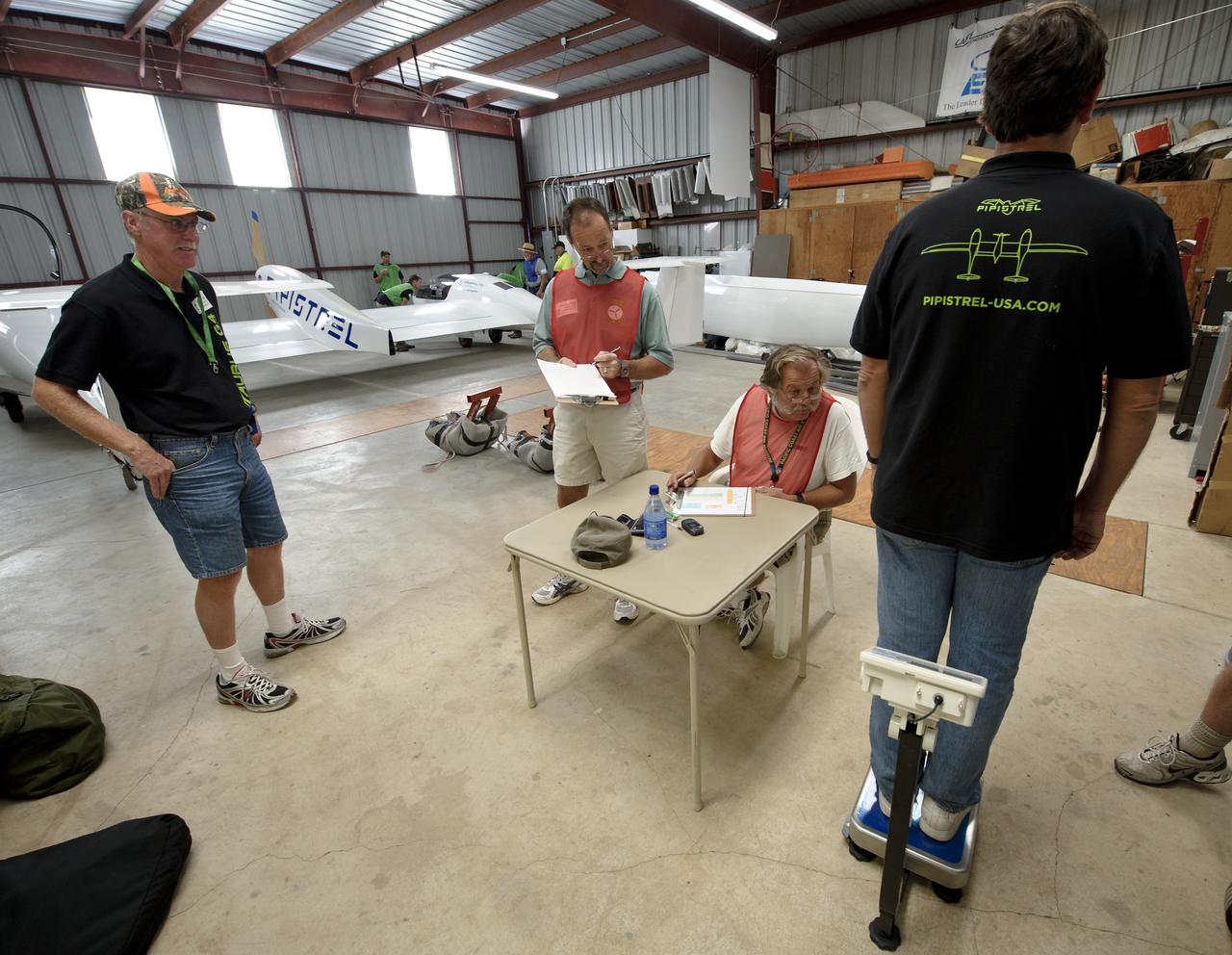 Pipistrel-USA Pilot David Morss, left, CAFE Foundation Weights Chief Wayne Cook, 2nd from left, and Weight crew member Ron Stout look on as Pipistrel-USA Pilot Robin Reid is weighed-in during the 2011 Green Flight Challenge, sponsored by Google, at the Charles M. Schulz Sonoma County Airport in Santa Rosa, Calif. on Monday, Sept. 26, 2011. NASA and the Comparative Aircraft Flight Efficiency (CAFE) Foundation are having the challenge with the goal to advance technologies in fuel efficiency and reduced emissions with cleaner renewable fuels and electric aircraft. Photo Credit: (NASA/Bill Ingalls)