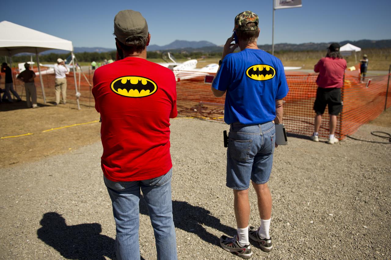Pipistrel-USA Pilots Robin Reid, left, and David Morss, talk on their cell phones shortly after participating in the miles per gallon (MPG) flight in their Taurus G4 aircraft during the 2011 Green Flight Challenge, sponsored by Google, at the Charles M. Schulz Sonoma County Airport in Santa Rosa, Calif. on Tuesday, Sept. 27, 2011. NASA and the Comparative Aircraft Flight Efficiency (CAFE) Foundation are having the challenge with the goal to advance technologies in fuel efficiency and reduced emissions with cleaner renewable fuels and electric aircraft. Photo Credit: (NASA/Bill Ingalls)