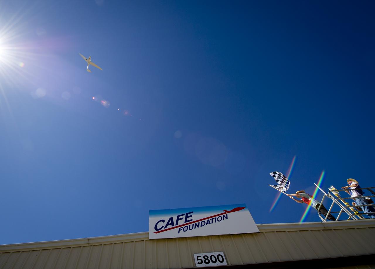 The checkered flag is waved as the PhoEnix aircraft crosses the finish line of the miles per gallon (MPG) flight during the 2011 Green Flight Challenge, sponsored by Google, at the Charles M. Schulz Sonoma County Airport in Santa Rosa, Calif. on Tuesday, Sept. 27, 2011.  NASA and the Comparative Aircraft Flight Efficiency (CAFE) Foundation are having the challenge with the goal to advance technologies in fuel efficiency and reduced emissions with cleaner renewable fuels and electric aircraft. Photo Credit: (NASA/Bill Ingalls)