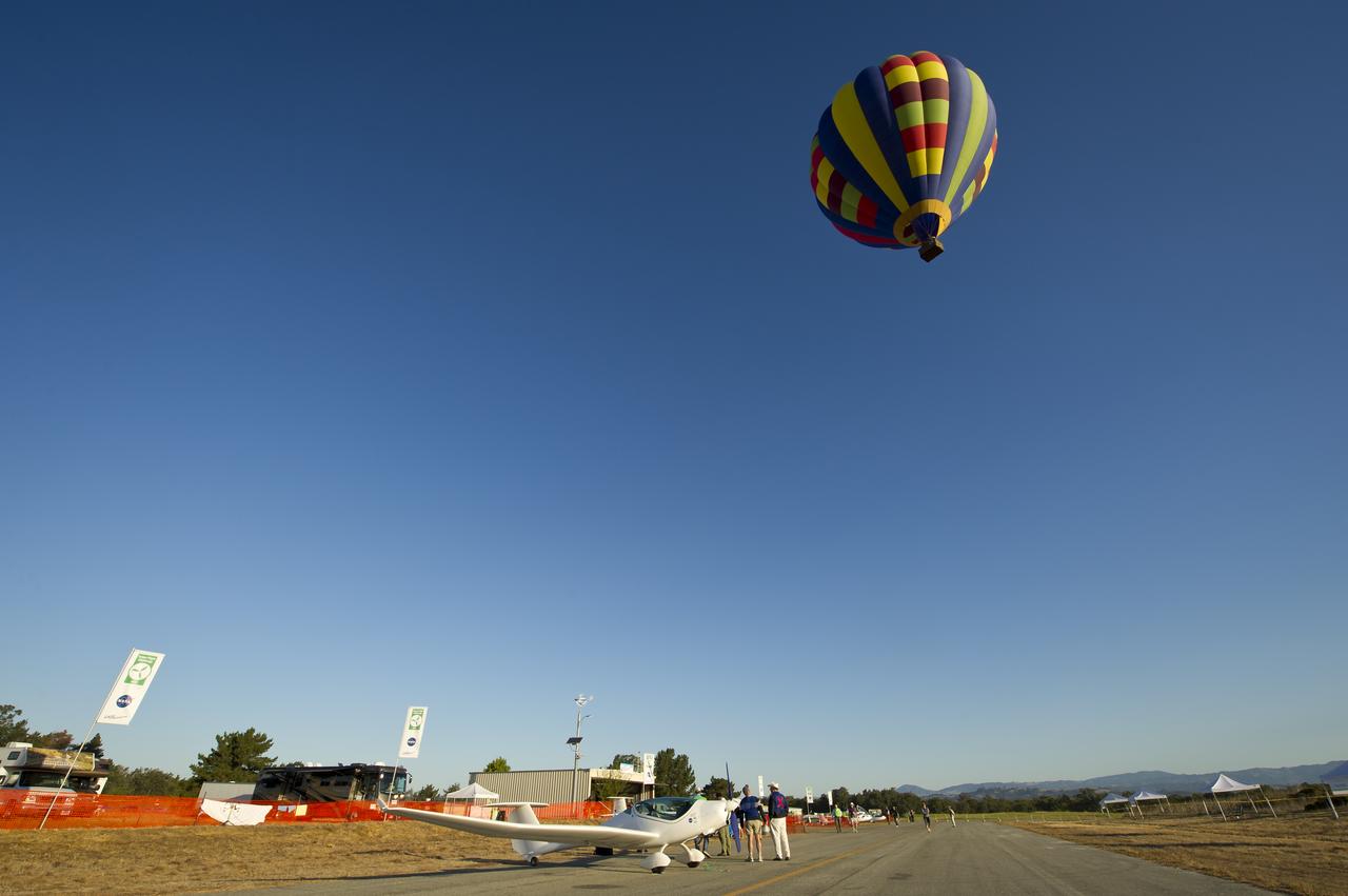 A hot air balloon passes over the campus of the 2011 Green Flight Challenge, sponsored by Google, at the Charles M. Schulz Sonoma County Airport in Santa Rosa, Calif. on Thursday, Sept. 29, 2011. NASA and the Comparative Aircraft Flight Efficiency (CAFE) Foundation are having the challenge with the goal to advance technologies in fuel efficiency and reduced emissions with cleaner renewable fuels and electric aircraft. Photo Credit: (NASA/Bill Ingalls)