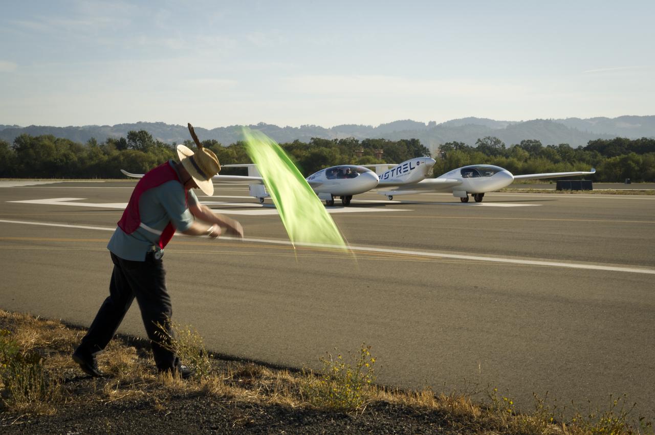 CAFE Foundation Hanger Boss Mike Fenn waves the speed competition start flag for the Pipistrel-USA, Taurus G4 aircraft during the 2011 Green Flight Challenge, sponsored by Google, at the Charles M. Schulz Sonoma County Airport in Santa Rosa, Calif. on Thursday, Sept. 29, 2011. NASA and the Comparative Aircraft Flight Efficiency (CAFE) Foundation are having the challenge with the goal to advance technologies in fuel efficiency and reduced emissions with cleaner renewable fuels and electric aircraft. Photo Credit: (NASA/Bill Ingalls)