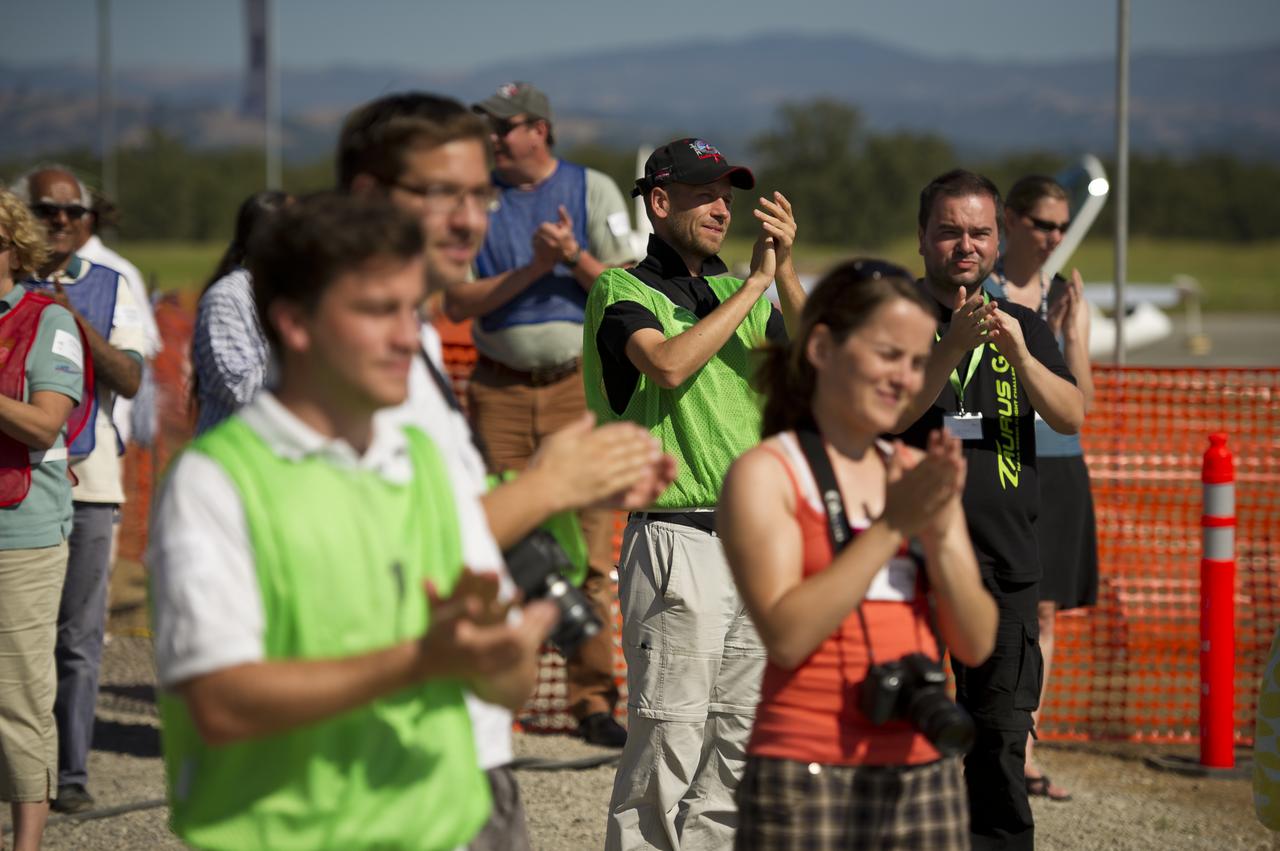 Various team members applaud as aircraft return from the speed competition during the 2011 Green Flight Challenge, sponsored by Google, held at the Charles M. Schulz Sonoma County Airport in Santa Rosa, Calif. on Thursday, Sept. 29, 2011. NASA and the Comparative Aircraft Flight Efficiency (CAFE) Foundation are having the challenge with the goal to advance technologies in fuel efficiency and reduced emissions with cleaner renewable fuels and electric aircraft. Photo Credit: (NASA/Bill Ingalls)