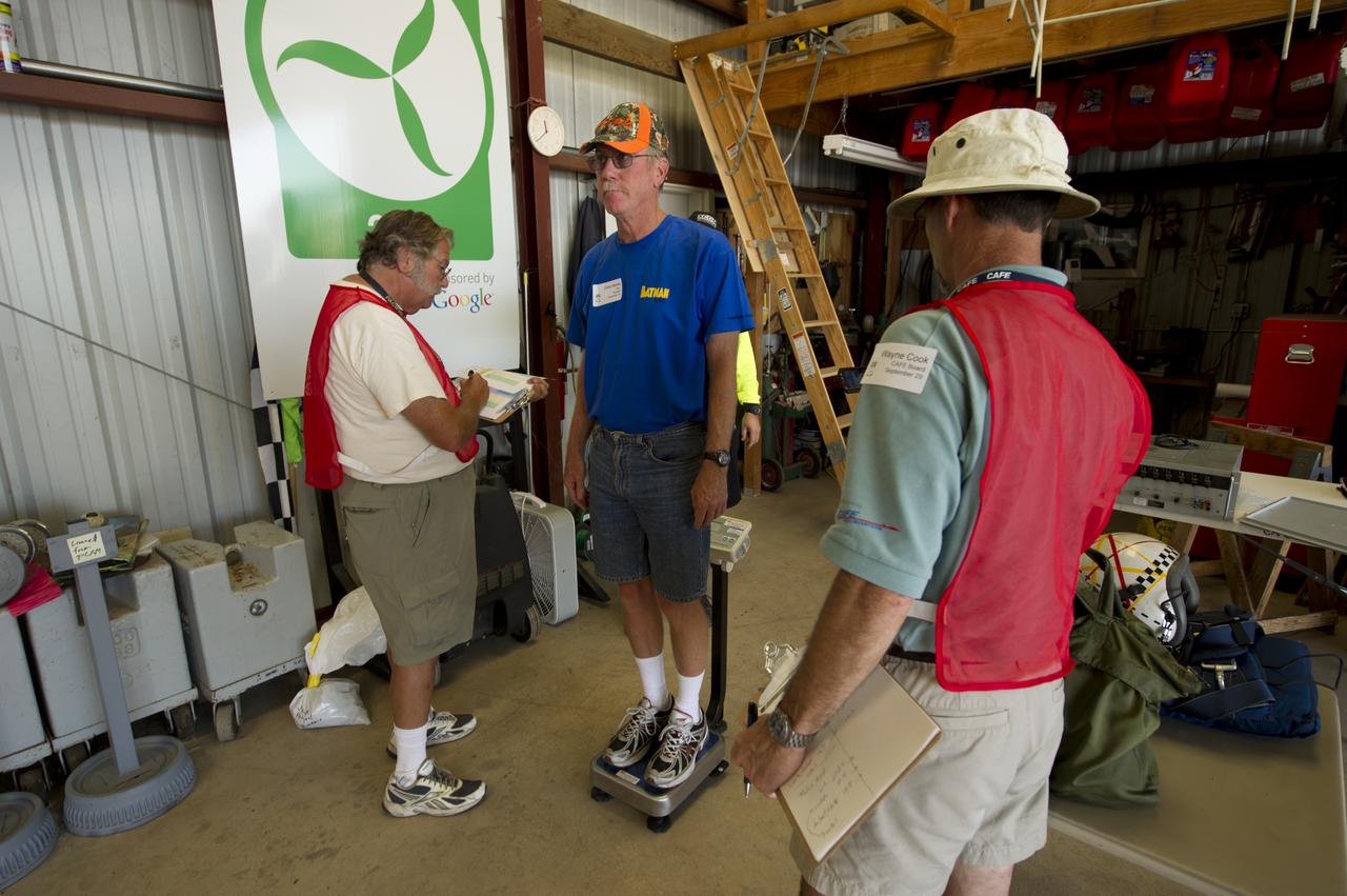 Pipistrel Taurus G4 Pilot David Morss, center, is is weighed-in as CAFE Foundation Weights Chief Wayne Cook, right, and Weight crew member Ron Stout look on during the 2011 Green Flight Challenge, sponsored by Google, held at the Charles M. Schulz Sonoma County Airport in Santa Rosa, Calif. on Thursday, Sept. 29, 2011. NASA and the Comparative Aircraft Flight Efficiency (CAFE) Foundation are having the challenge with the goal to advance technologies in fuel efficiency and reduced emissions with cleaner renewable fuels and electric aircraft. Photo Credit: (NASA/Bill Ingalls)