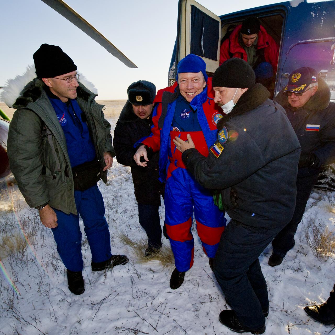 Expedition 29 Commander Mike Fossum smiles as he is helped from a Russian Search and Rescue all terrain vehicle (ATV) to his helicopter after he and Expedition 29 Flight Engineers Sergei Volkov and Satoshi Furukawa landed in their Soyuz TMA-02M spacecraft in a remote area outside of the town of Arkalyk, Kazakhstan, on Tuesday, Nov. 22, 2011. NASA Astronaut Fossum, Russian Cosmonaut Volkov and JAXA (Japan Aerospace Exploration Agency) Astronaut Furukawa are returning from more than five months onboard the International Space Station where they served as members of the Expedition 28 and 29 crews. Photo Credit: (NASA/Bill Ingalls)