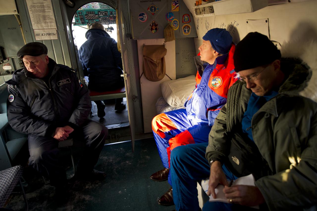 Expedition 29 Commander Mike Fossum, center, looks at the various mission stickers onboard a Russian Search and Rescue helicopter after he and Expedition 29 Flight Engineers Sergei Volkov and Satoshi Furukawa landed in their Soyuz TMA-02M spacecraft in a remote area outside of the town of Arkalyk, Kazakhstan, on Tuesday, Nov. 22, 2011. NASA Astronaut Fossum, Russian Cosmonaut Volkov and JAXA (Japan Aerospace Exploration Agency) Astronaut Furukawa are returning from more than five months onboard the International Space Station where they served as members of the Expedition 28 and 29 crews. Photo Credit: (NASA/Bill Ingalls)