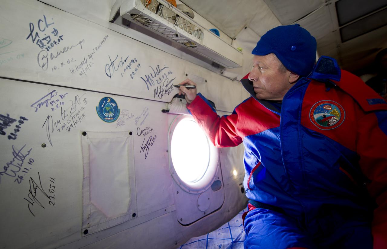 Expedition 29 Commander Mike Fossum performs the traditional signing of the inside the Russian Search and Rescue helicopter after he and Expedition 29 Flight Engineers Sergei Volkov and Satoshi Furukawa landed in their Soyuz TMA-02M spacecraft in a remote area outside of the town of Arkalyk, Kazakhstan, on Tuesday, Nov. 22, 2011. NASA Astronaut Fossum, Russian Cosmonaut Volkov and JAXA (Japan Aerospace Exploration Agency) Astronaut Furukawa are returning from more than five months onboard the International Space Station where they served as members of the Expedition 28 and 29 crews. Photo Credit: (NASA/Bill Ingalls)