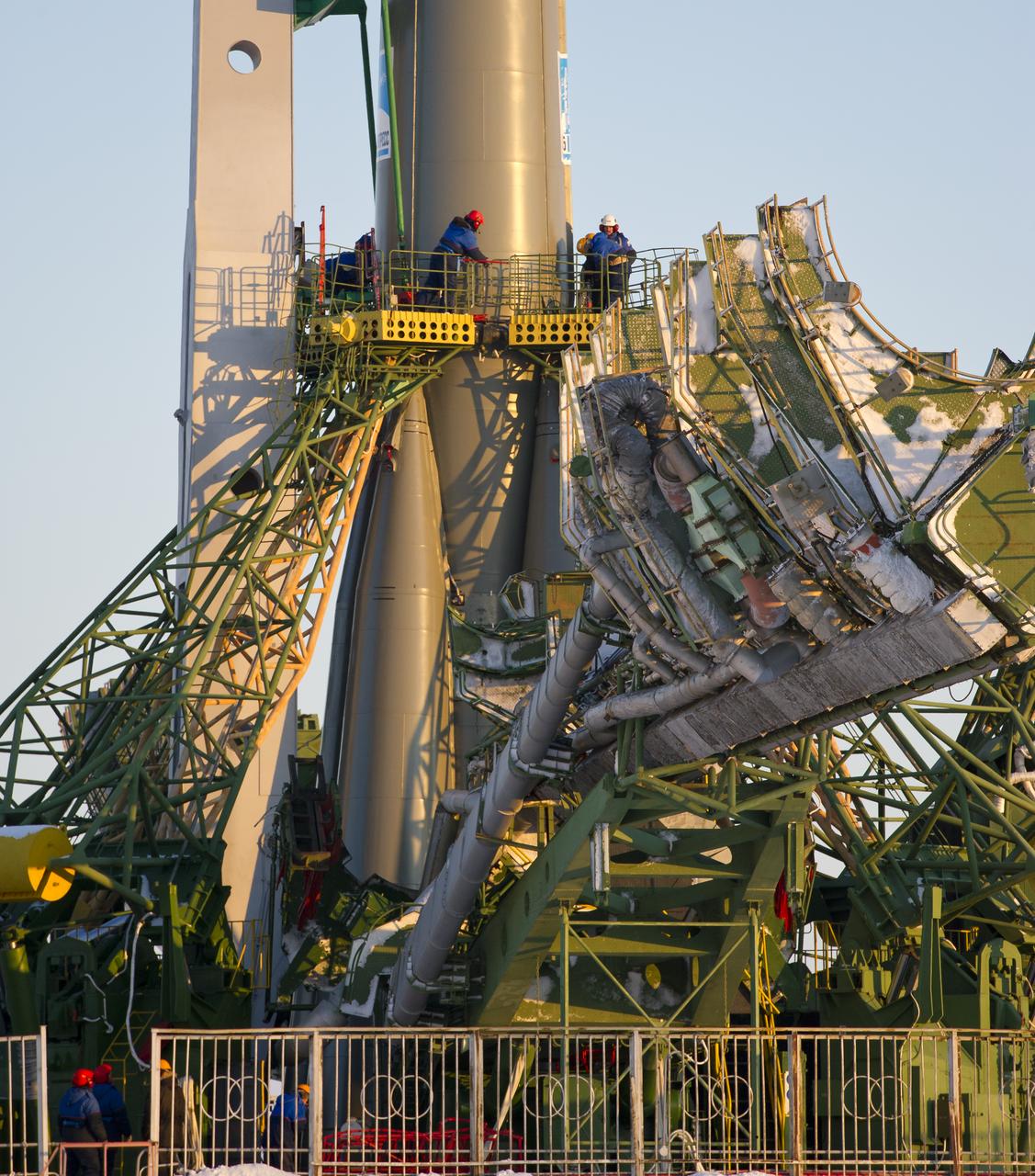 Launch pad engineers at the Baikonur Cosmodrome in Kazakhstan are dwarfed by the large gantry mechanisms at the base of the Soyuz TMA-03M rocket following its rollout to the pad on Monday, Dec. 19, 2011.  The rocket is being prepared for launch on December 21 to carry the crew of Expedition 30 to the International Space Station.  Photo Credit:  (NASA/Carla Cioffi)