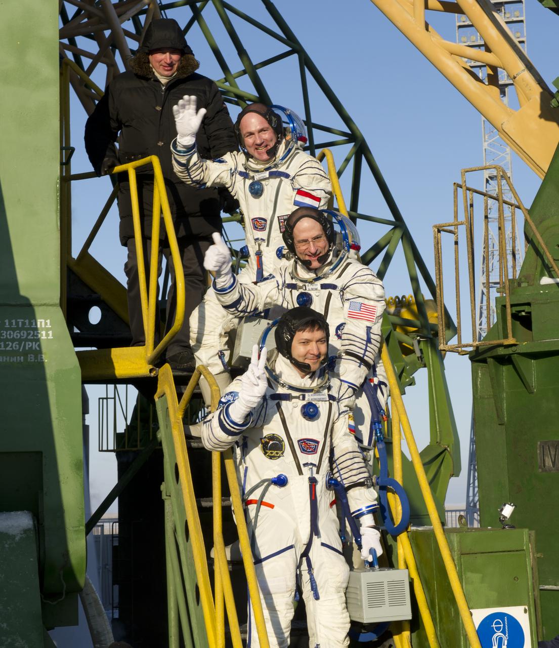 Expedition 30 Soyuz Commander Oleg Kononenko, bottom, NASA Flight Engineer Don Pettit of the U.S., and ESA (European Space Agency) Flight Engineer Andre Kuipers, top, wave farewell from the base of the Soyuz rocket at the Baikonur Cosmodrome in Kazakhstan, Wednesday, Dec. 21, 2011. Kononenko, Pettit and Kuipers launched in their Soyuz TMA-03M rocket from the Baikonur Cosmodrome at 7:16 p.m. local time. (Photo Credit: NASA/Carla Cioffi)
