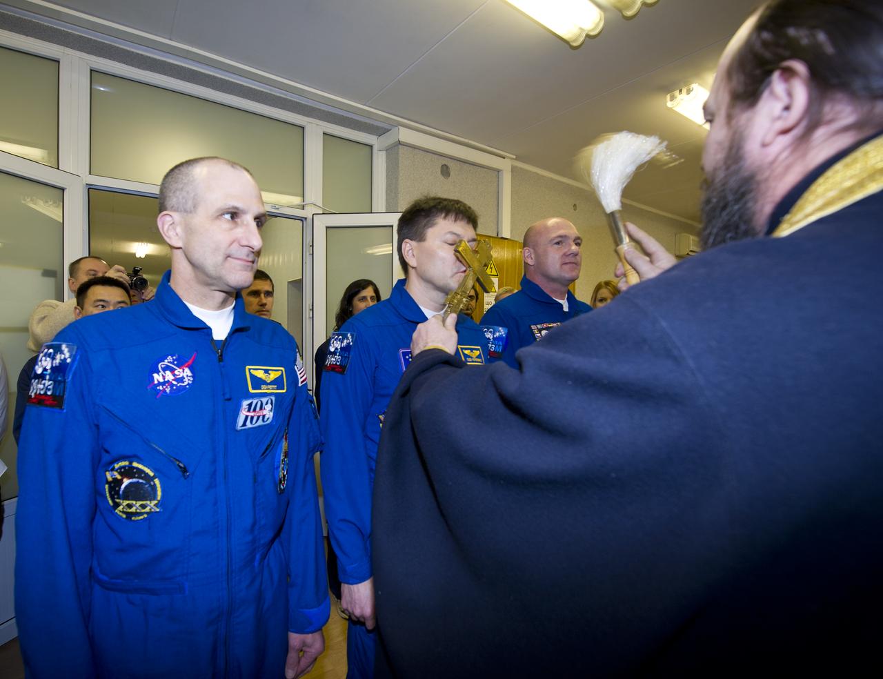Expedition 30 Soyuz Commander Oleg Kononenko, center, receives the traditional blessing from a Russian Orthodox priest at the Cosmonaut Hotel on the day before his Soyuz launch to the International Space Station, Wednesday, Dec. 21, 2011 in Baikonur, Kazakhstan. Photo Credit: (NASA/Carla Cioffi)