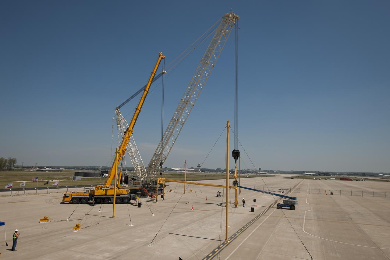Workers use two cranes to position the sling that will be used to demate the space shuttle Discovery, Monday, April 16, 2012, at the Apron W area of Washington Dulles international Airport in Sterling, Va. The sling will be used to demate the space shuttle Discovery from the 747 Shuttle Carrier Aircraft (SCA) once it arrives. Discovery, the first orbiter retired from NASA’s shuttle fleet, completed 39 missions, spent 365 days in space, orbited the Earth 5,830 times, and traveled 148,221,675 miles. NASA will transfer Discovery to the National Air and Space Museum to begin its new mission to commemorate past achievements in space and to educate and inspire future generations of explorers. Photo Credit: (NASA/Bill Ingalls)